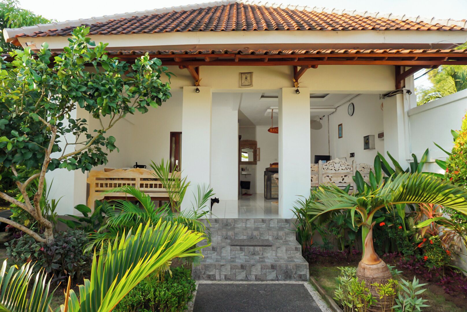 A house with a tiled roof, a covered porch, and a stone staircase leading to the entrance.
