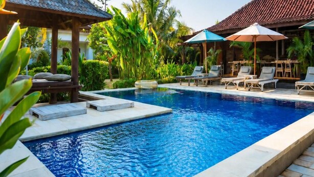 A swimming pool with lounge chairs and umbrellas, surrounded by greenery and a gazebo. - Uluwatu Jungle Villa (Pecatu)