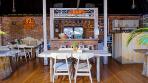 A rustic bar area with wooden furniture and a brick wall backdrop. - Uluwatu Jungle Villa (Pecatu)
