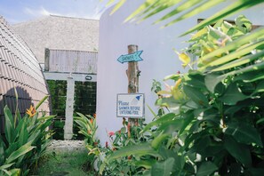 A signpost with directions to a shower and pool, surrounded by lush greenery. - Uluwatu Jungle Villa (Pecatu)