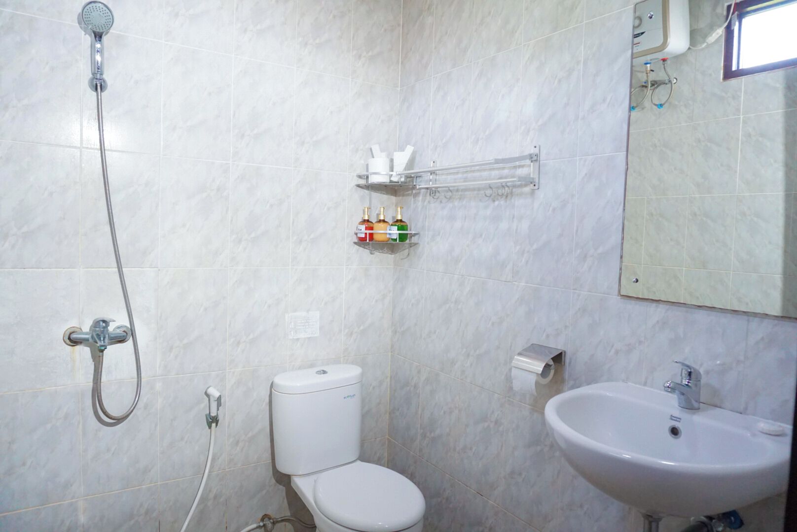 Et badeværelse med toilet, håndvask og bruser.