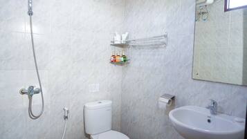 Et badeværelse med toilet, håndvask og bruser.