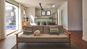 A modern living room with a sofa, a dining area, and a kitchen in the background. - Private Villa with swimming pool & barbecue (Funchal)
