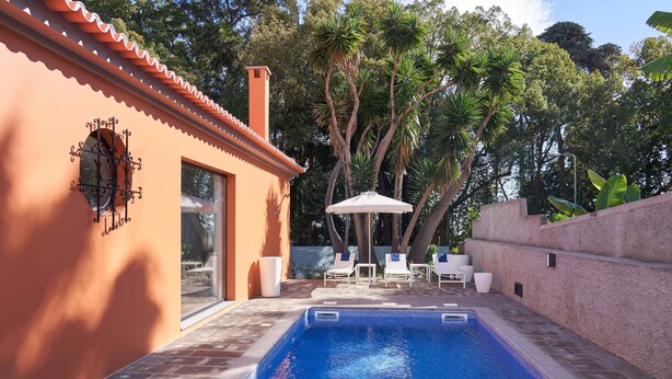 A swimming pool with a tiled edge, surrounded by a brick patio. There are lounge chairs and a white umbrella. - Private Villa with swimming pool & barbecue (Funchal)