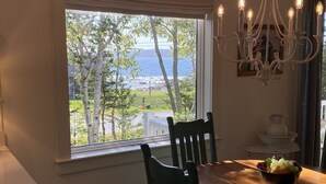 Uma sala de jantar com vista para o oceano, um candelabro e uma tigela de frutas na mesa.