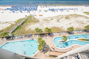 A beach resort with multiple swimming pools, sun loungers, and beach umbrellas. - The Oasis at Orange Beach, formerly known as Phoenix West II, Unit 706 (Orange Beach)