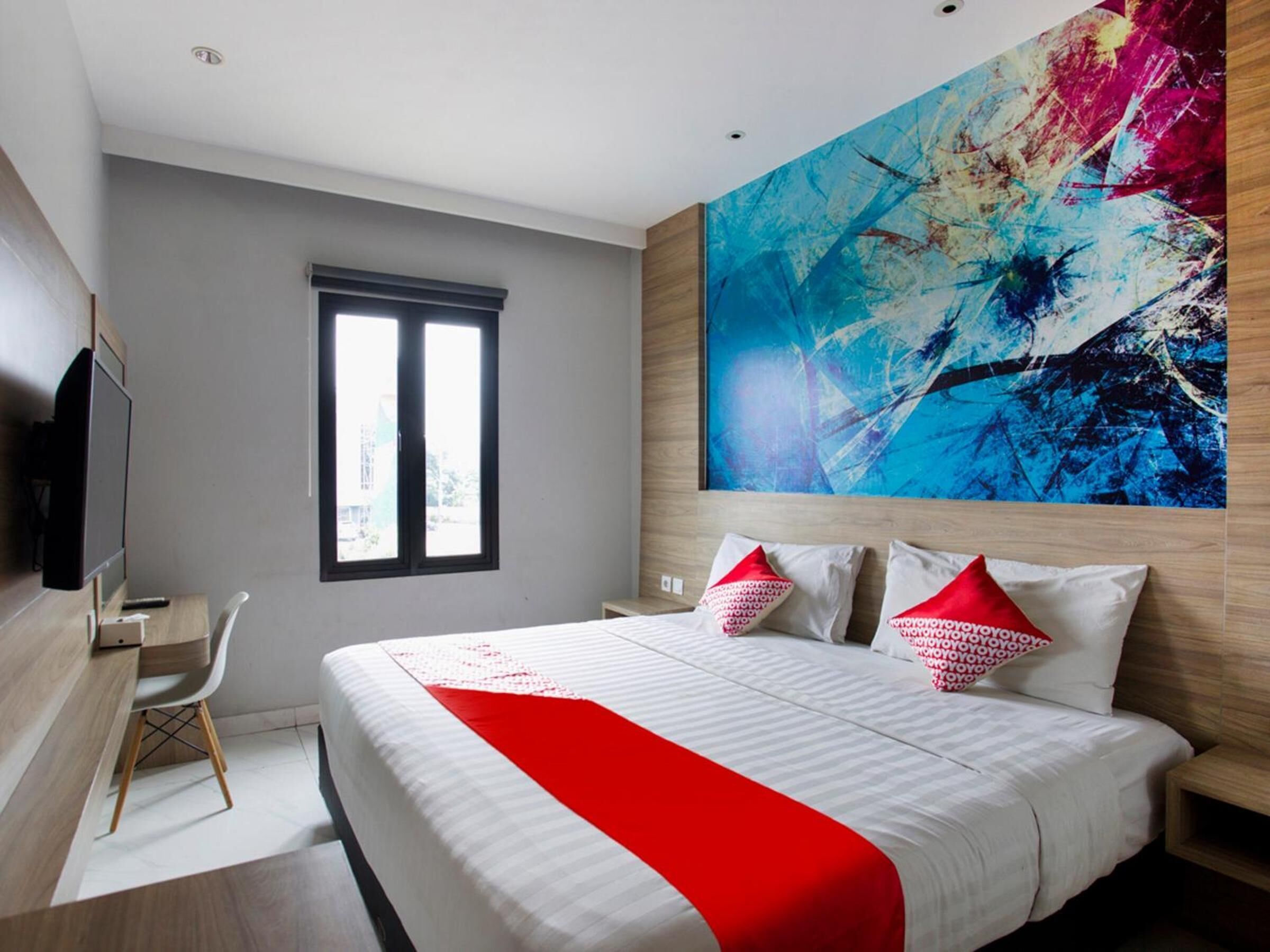 A modern hotel room with a large bed, a desk, and a TV.
