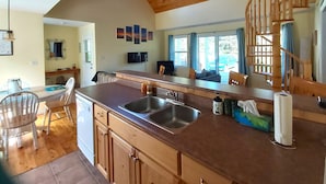 A spacious kitchen with a large island, wooden ceiling, and a view of the outdoors. - Little Eden Summer Beach Home  (Canoe Cove)