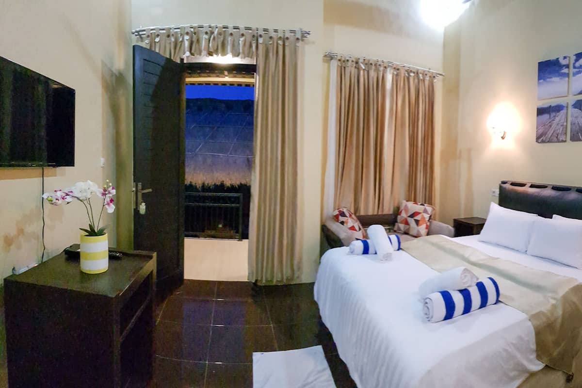 A hotel room with a bed, a bedside table, a TV, a window with curtains, and a wall with a picture.