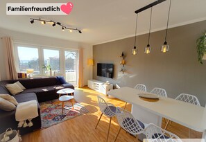 A modern living room with a sofa, TV, dining table, and chairs.