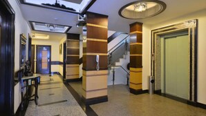 Een hotel lobby met een modern design, met een trap, een receptiebalie en een grote spiegel.