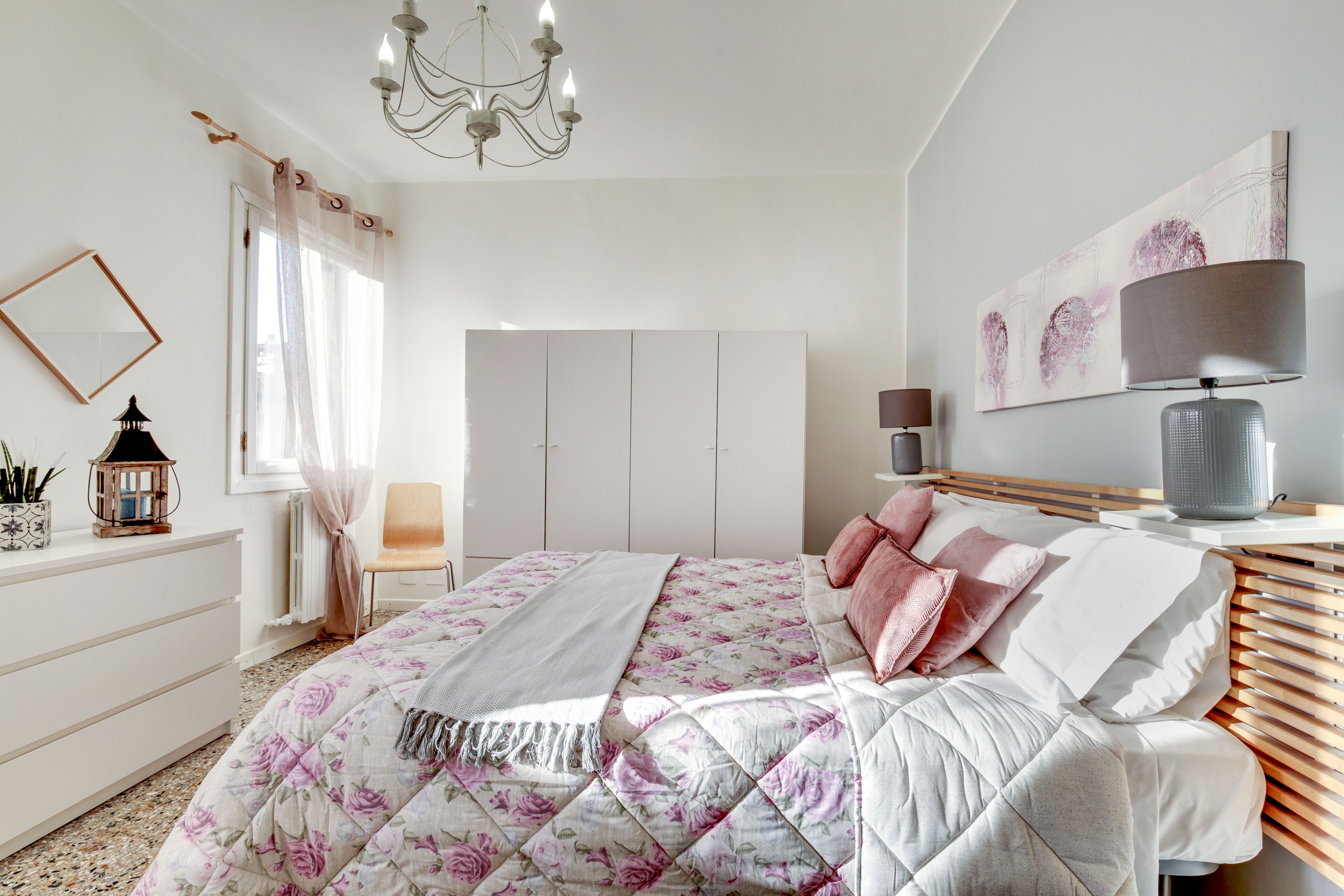 A bedroom with a bed, a dresser, a chair, a lamp, and a painting on the wall.