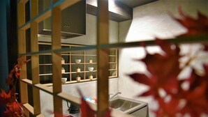 A kitchen with a modern design, featuring a stainless steel range hood, a sink, and a window with a view of the outside. - Chika Miyabi (Kyoto)