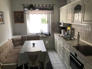Cocina compacta con comedor, que incluye un sofá, mesa y una ventana con cortinas.