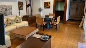 A living room with a sofa, a coffee table, a dining table with chairs, a fan, and a cabinet. - Private Thai style villa with private  pool (Koh Samui)