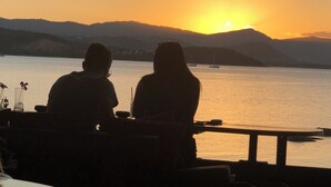 Two people sitting at a table with a view of a sunset over water and hills. - Private Thai style villa with private  pool (Koh Samui)