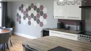 Una cocina moderna con un diseño de pared hexagonal, una mesa de comedor de madera y luces colgantes.