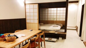 A compact room with a wooden table, chairs, a bed with a futon, and a sliding shoji screen. - Chika Ichiyin (Kyoto)