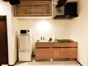 A compact kitchen with a microwave, refrigerator, sink, and wooden cabinets.