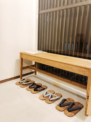 A wooden bench with a glass panel underneath, positioned against a wall with a window. - Chika Ichiyin (Kyoto)
