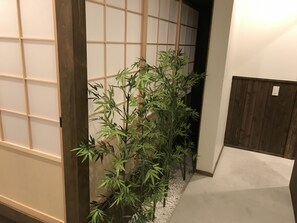 Experience a serene atmosphere in this traditional Japanese-style room, featuring a sliding shoji screen door and a bamboo plant.