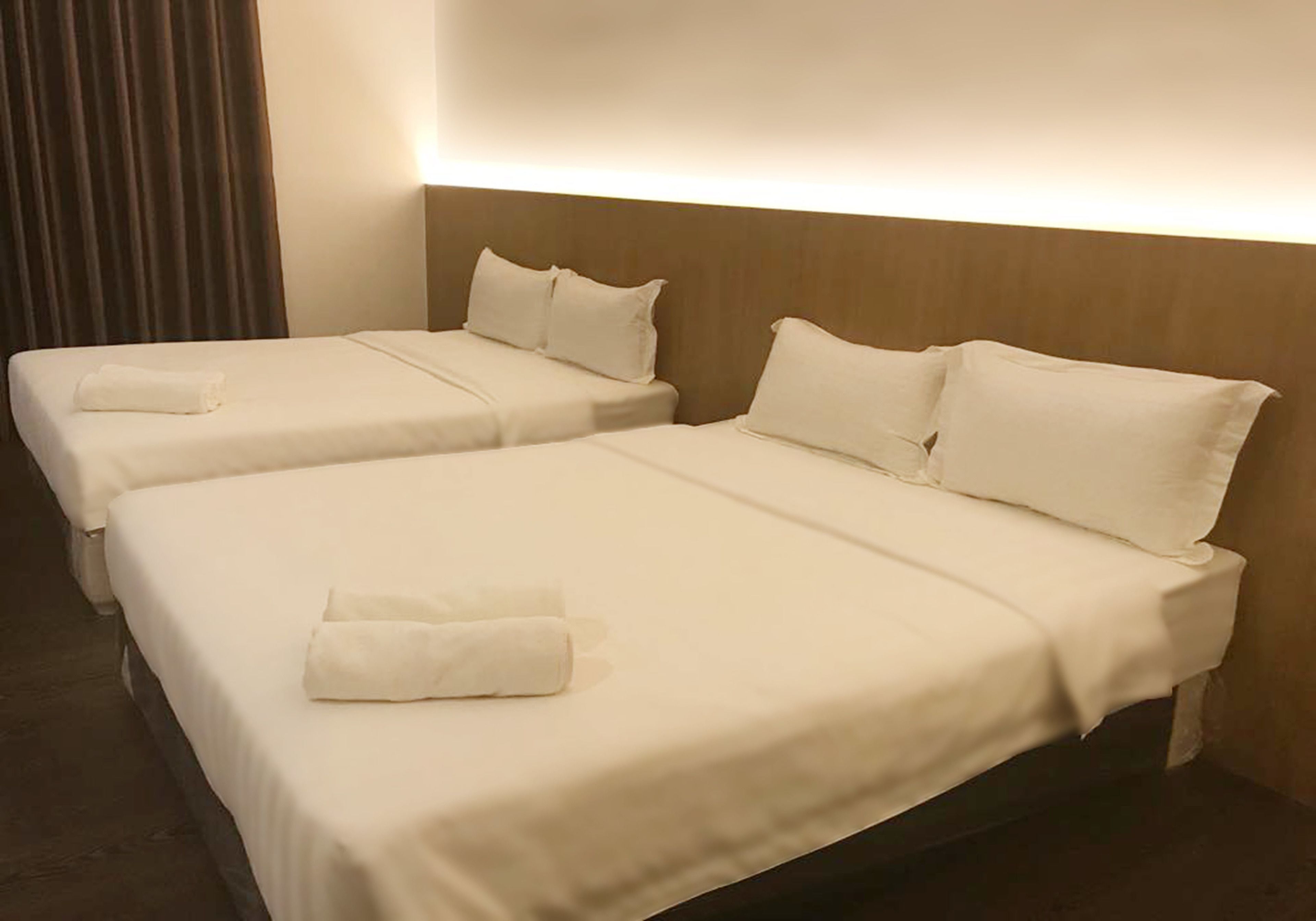 A hotel room with two beds, each with white linens and pillows, and a headboard with built-in lighting.