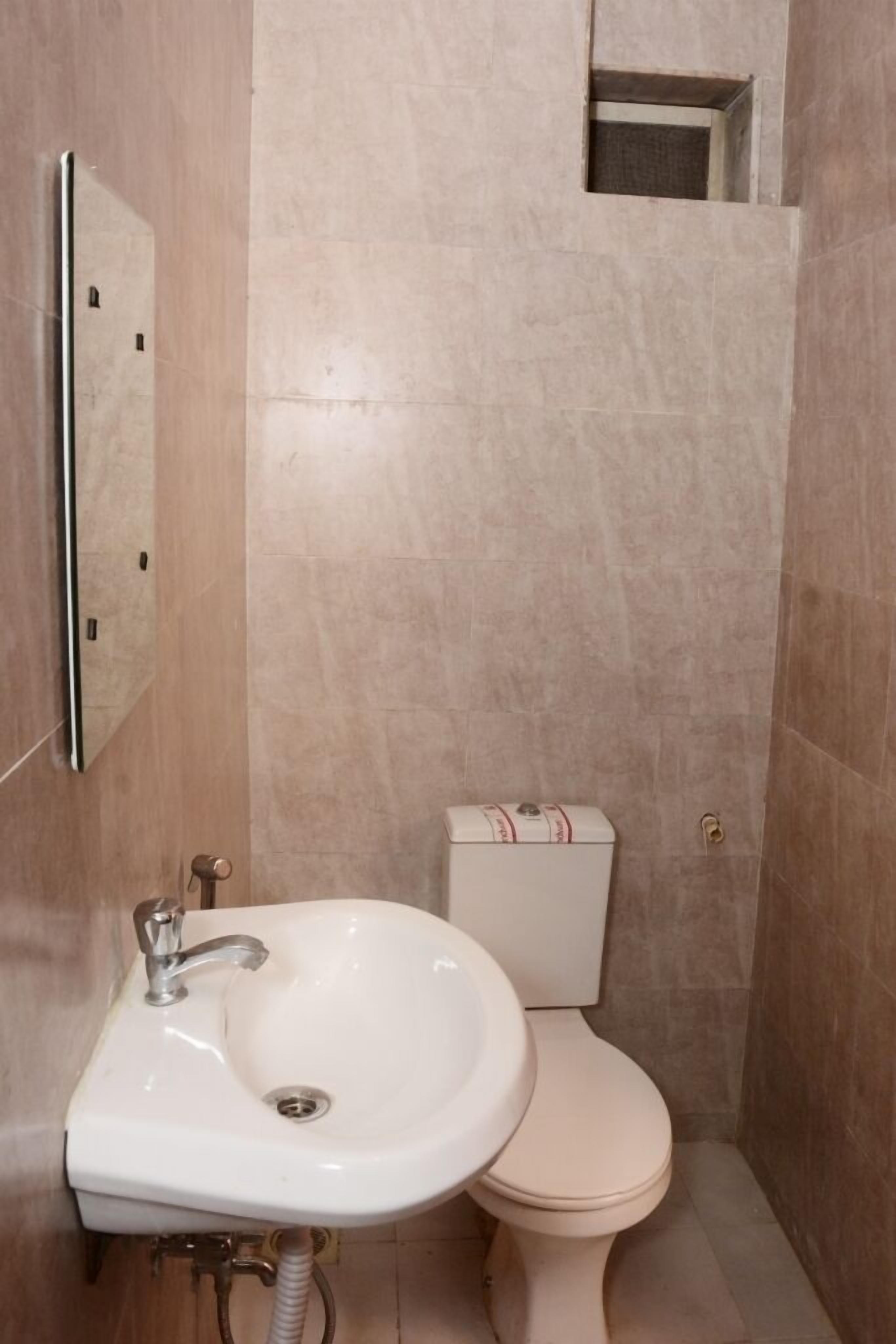 A small bathroom with a white sink, toilet, and a mirror.