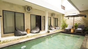 Un área junto a la piscina con asientos, piscina y un muro de piedra.