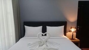 Una cama bien hecha con una decoración de toallas con forma de cisne sobre la colcha.
