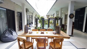 Un comedor con una mesa larga, sillas de madera y vista a una piscina.