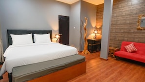 Un dormitorio moderno con una cama grande, un sofá rojo y una mesa de comedor de madera.
