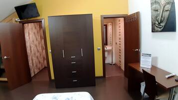 Ein Hotelzimmer mit einem Bett, einem Schreibtisch, einem Kleiderschrank und einem durch eine offene Tür einsehbaren Badezimmer.
