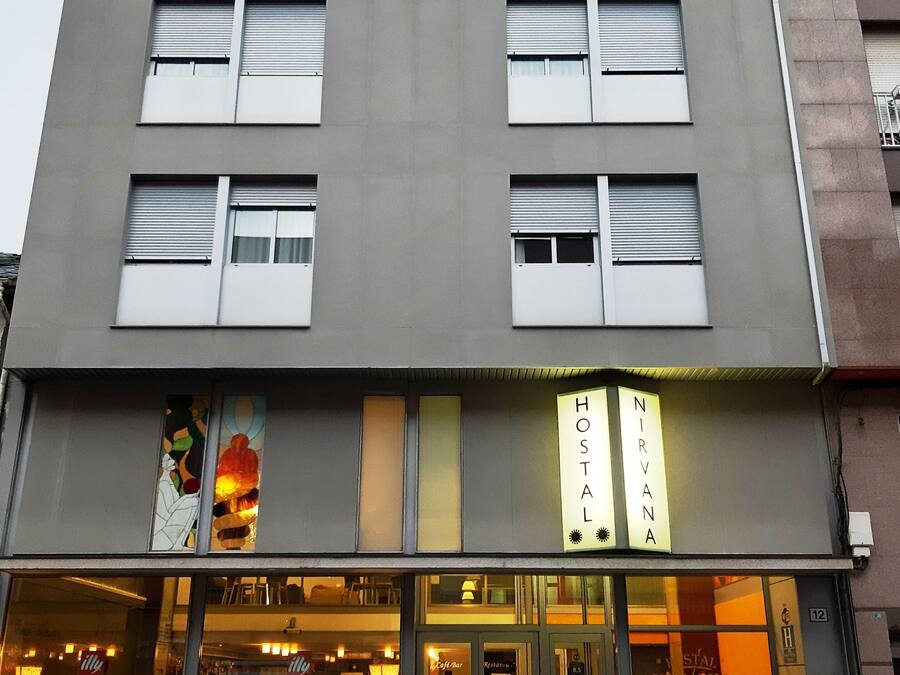 A hotel with a modern facade, large windows, and a sign reading "NIRVANA HOSTAL".