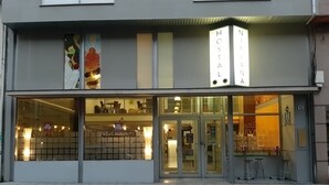 A modern hotel with a glass facade, a sign reading "HOSTAL NIRVANA," and a visible restaurant sign inside. - Hostal Nirvana (Ponferrada)
