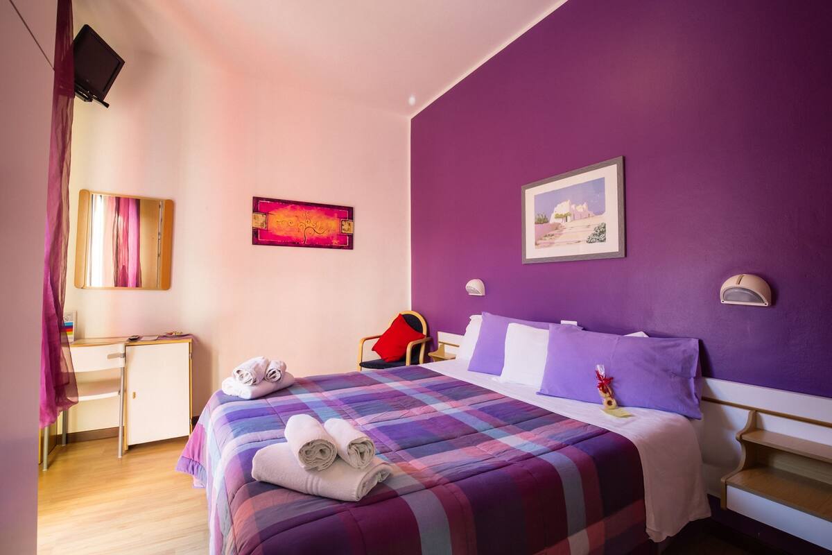 A hotel room with a bed, a desk, and a chair.