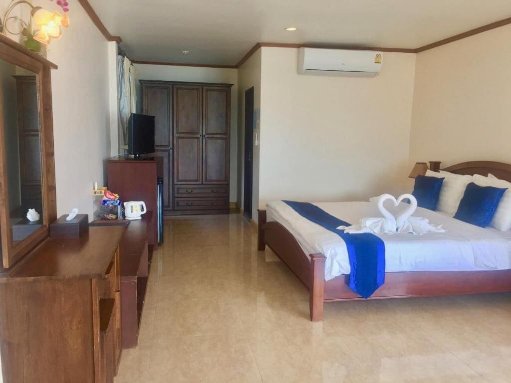 Ein Hotelzimmer mit einem Holzbett, einem Fernseher auf einem Tisch, einem Schreibtisch und einem Kleiderschrank.