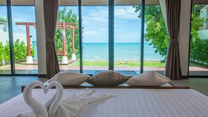 Een hotelkamer met een groot bed, uitzicht op zee en een pergola buiten.