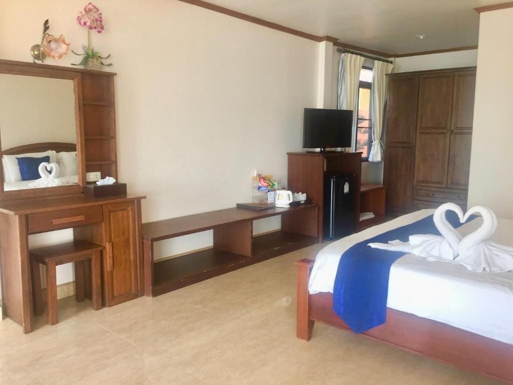 A hotel room with a bed, a desk, a television, and a wardrobe.