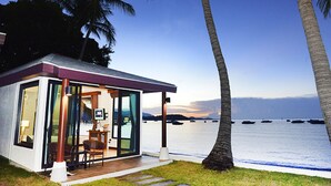 Een modern huis met een glazen deur, een klein terras en uitzicht op de oceaan.