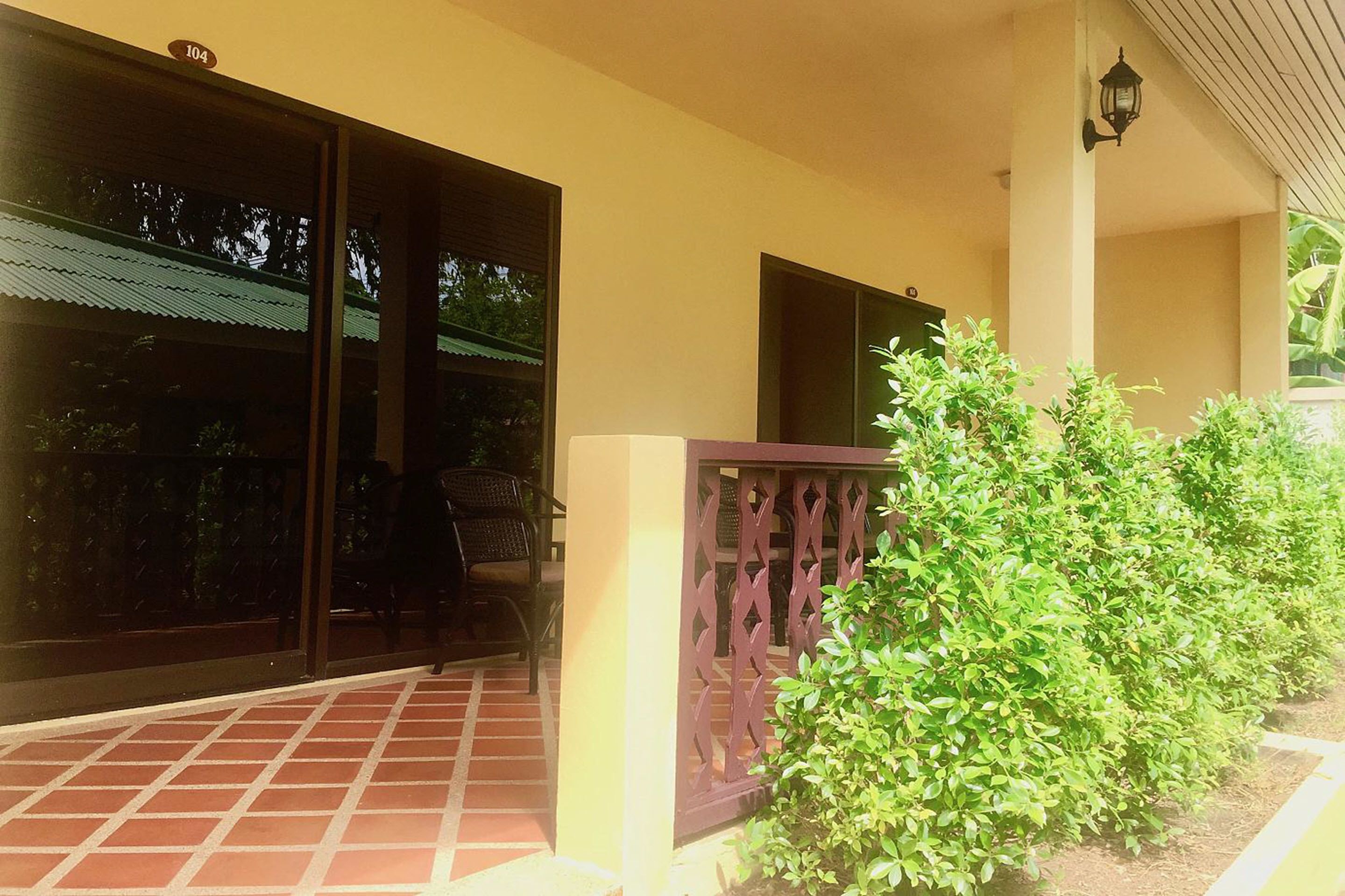 A building with a tiled patio, a wooden fence, and a small garden area.