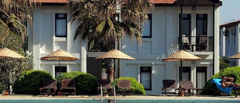 Una piscina al aire libre, sombrillas, sillones reclinables de piscina