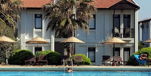 Un hotel con piscina, sillones de descanso y sombrillas.