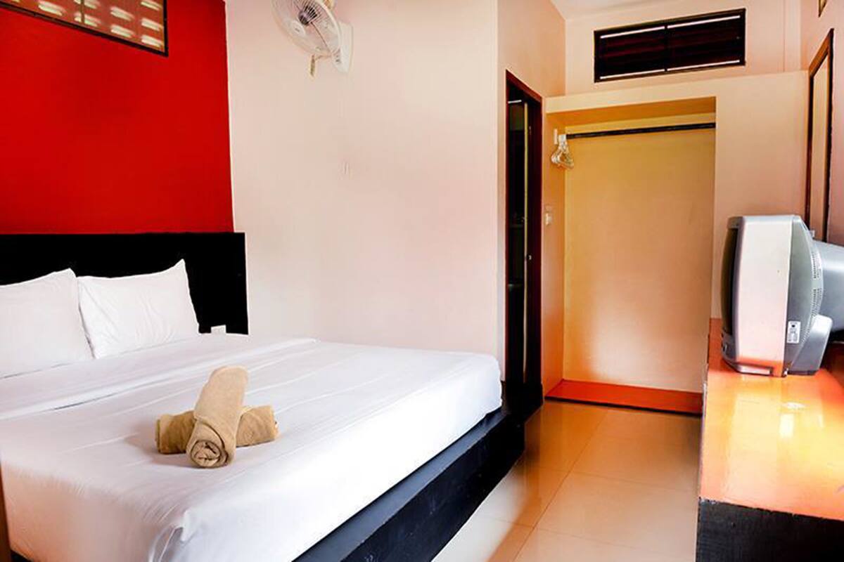 Une chambre d’hôtel avec un lit, une télévision et une armoire.