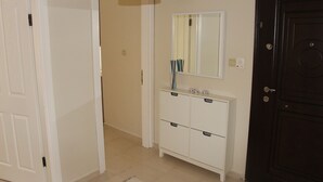 A hallway with a white door, a dark door, and a white cabinet with drawers. - Kinzi House (Çanakkale)