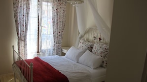 A bedroom with a bed, white curtains, a chandelier, and a red blanket. - Kinzi House (Çanakkale)