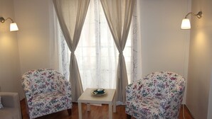 A room with two floral-patterned armchairs, a small table with a bowl, and a window with sheer curtains. - Kinzi House (Çanakkale)