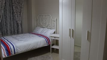 A bedroom with a bed, a wardrobe, and a desk.