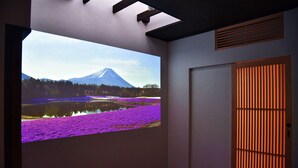 A room with a large projection of Mount Fuji, a wooden door, and a radiator. - Chika Odoru (Kyoto)