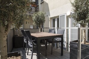 An outdoor patio with a table and chairs, surrounded by plants and a fence. - Brera Apartments in City Center (Milan)