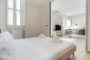 A hotel room with a bed, a desk, a TV, and a kitchenette. - Brera Apartments in City Center (Milan)